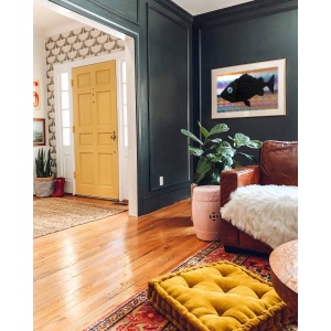 Nekol’s Fish #2 oil painting in a home interior: A single, surreal black fish floats across a vibrant, layered background of abstract, wave-like colors