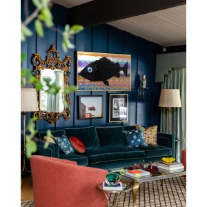 Nekol’s Fish #2 oil painting in a home interior: A single, surreal black fish floats across a vibrant, layered background of abstract, wave-like colors