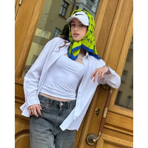 Blue butterfly silk scarf styled around the neck, showcasing lime and azure pattern.