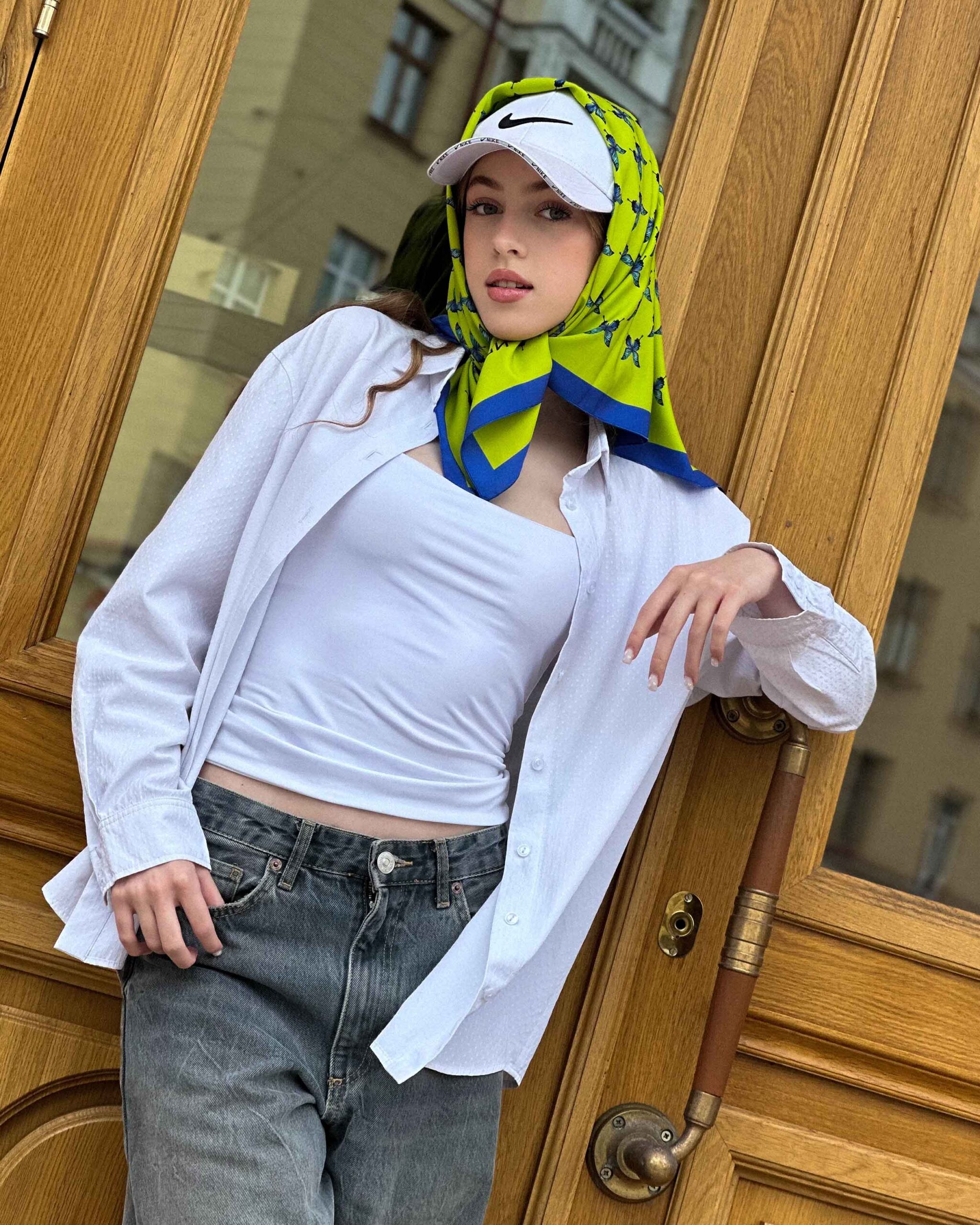 Blue butterfly silk scarf styled around the neck, showcasing lime and azure pattern.